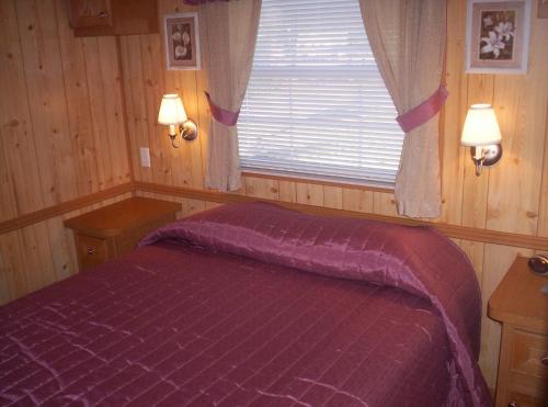 sypialnia z fioletowym łóżkiem i oknem w obiekcie Orlando RV Resort w Orlando
