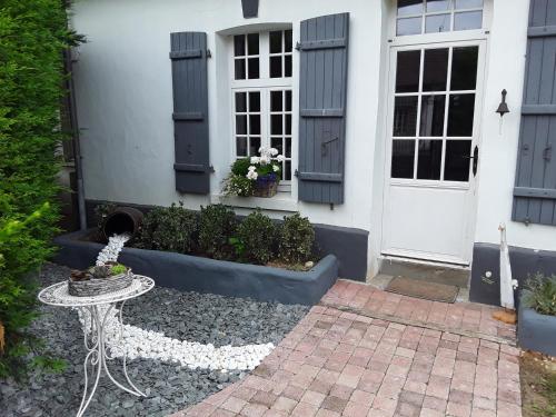 a white house with a table in front of a door at Au Moulin de Valérie in Frencq