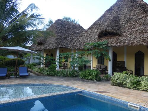 a villa with a swimming pool in front of a house at Kiwengwa Bungalow Boutique Resort in Kiwengwa