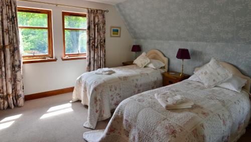 Un dormitorio con dos camas y una ventana. en Home Farm Bed and Breakfast, en Muir of Ord