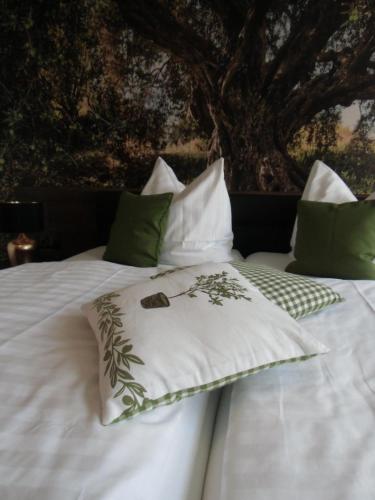 a white bed with green and white pillows on it at Hotel Trendtino in Eisenberg