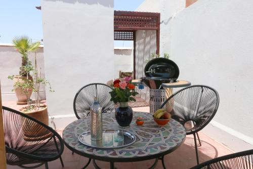 un tavolo con tre sedie e un tavolo con i fiori di Riad Merstane Marrakech a Marrakech