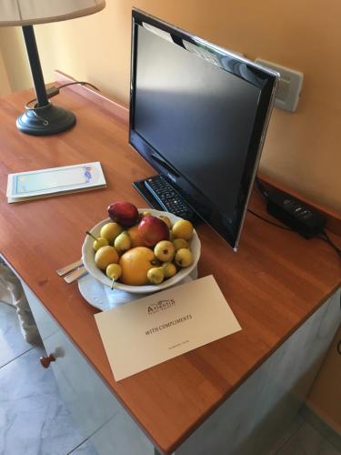 a desk with a bowl of fruit and a computer monitor at Atlantis Palace Hotel in Mascali