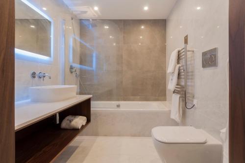 a bathroom with a toilet and a sink and a tub at The Duke Boutique Hotel in Victoria