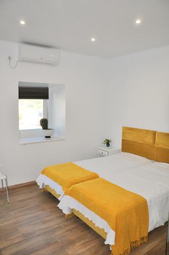 a bedroom with a large bed with a yellow blanket at Sleep In Bucelas in Bucelas