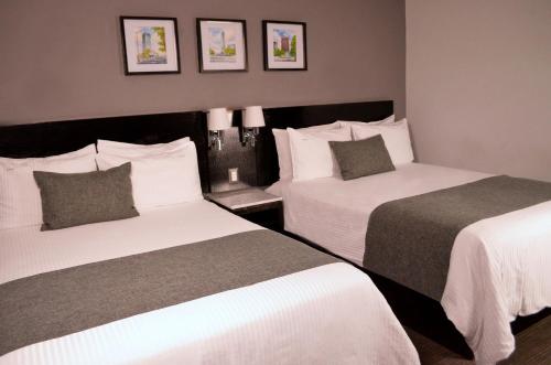 a hotel room with two beds with white sheets at LaiLa Hotel CDMX Reforma in Mexico City