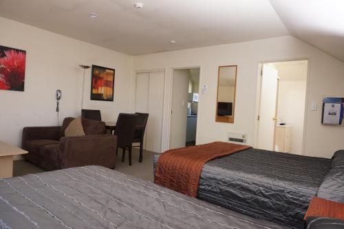 a hotel room with a bed and a couch and a chair at Sherborne Motor Lodge in Christchurch