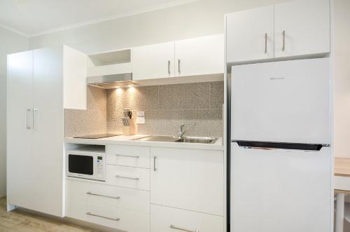 a kitchen with white cabinets and white appliances at Beach House Motel in Townsville