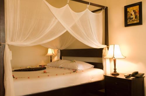 - une chambre avec un lit à baldaquin et des rideaux blancs dans l'établissement Cham Villas Resort, à Mui Ne