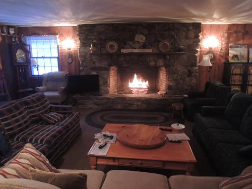 a living room with a fireplace with couches and a table at Turn of River Lodge in Killington