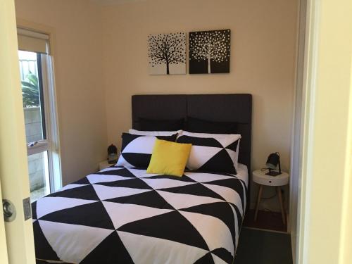 a bedroom with a black and white bed with a yellow pillow at Lyreen's Apartment in Auburn