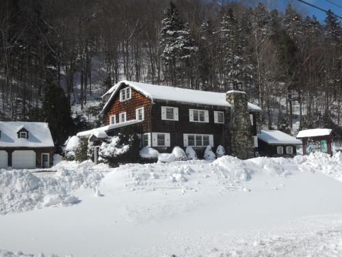 a house covered in snow in a yard at Turn of River Lodge in Killington