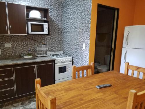 a kitchen with a table and a white refrigerator at Arbolada Talas del Tuyu in San Clemente del Tuyú