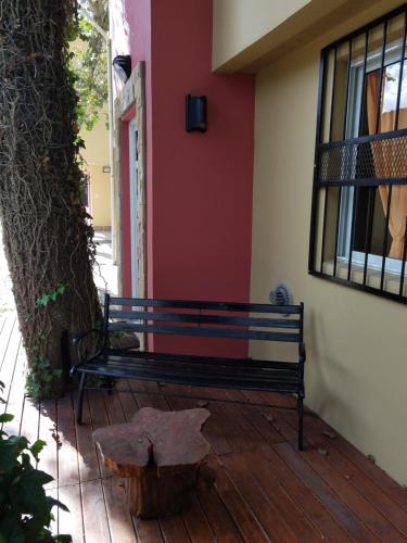 a bench sitting on a porch next to a tree at Arbolada Talas del Tuyu in San Clemente del Tuyú