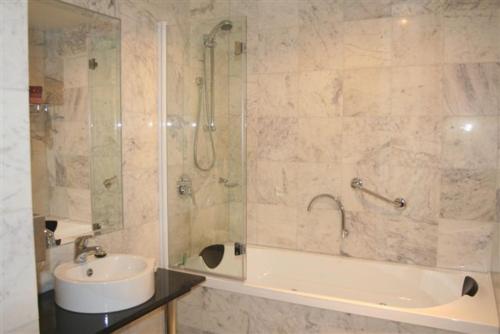 a bathroom with a tub and a sink and a shower at The Hotel Shamrock in Bendigo