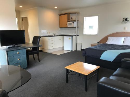 a hotel room with a bed and a desk and a couch at Pacific Harbour Motor Inn in Gisborne