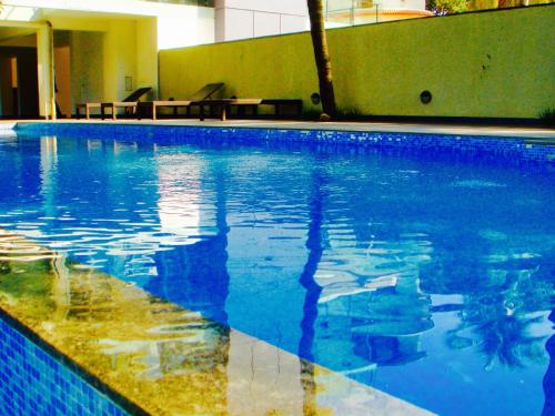 ein großer Pool mit blauem Wasser in einem Gebäude in der Unterkunft Luxurious 2BHK for Ultimate Holiday Experience in Goa, Candolim North Goa in Candolim