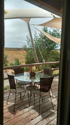 a table and chairs on a deck with an umbrella at Vinofilia Wine Country Inn in Valle de Guadalupe