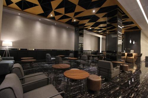 a lobby with tables and chairs and a wall at Forriz Hotel Yogyakarta in Yogyakarta