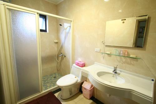 een badkamer met een douche, een toilet en een wastafel bij 鋐洋民宿 in Lugu