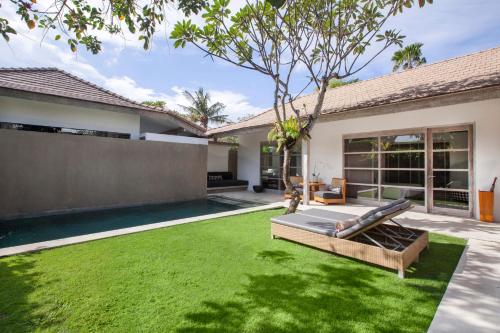 a backyard with a green lawn and a pool at Uma Sapna Seminyak in Seminyak