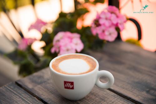 a cup of coffee sitting on a wooden table with flowers at Boutique Hotel Baku in Baku