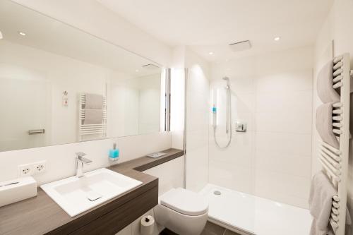 ein weißes Badezimmer mit Waschbecken und Toilette in der Unterkunft Boardinghouse am Wall in Salzgitter-Bad