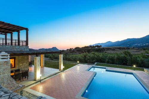 a villa with a swimming pool at dusk at Poseidon Villa, nestled in the picturesque south, By ThinkVilla in Lefkogeia