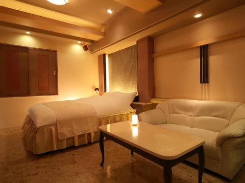 a hotel room with a bed and a couch and a table at Hotel Fine Garden Nara Horai in Nara