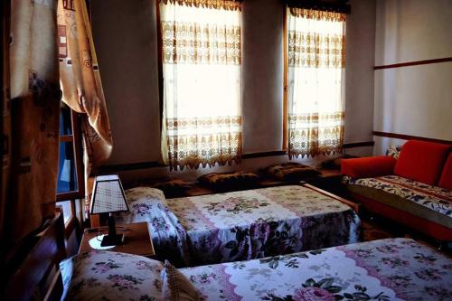 a room with three beds and a couch and windows at Guest House Vasili in Berat