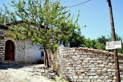 a stone wall with a tree and a street sign at Guest House Vasili in Berat