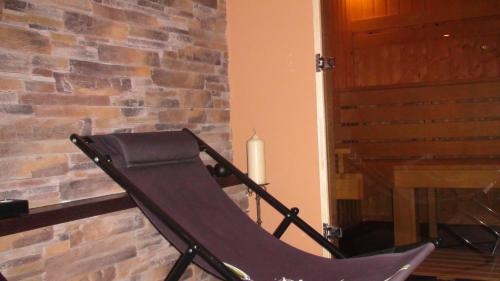 a black rocking chair next to a brick fireplace at Family Hotel Strannopriemnitza in Oreshak