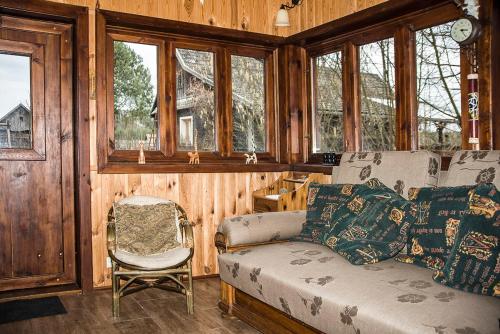a living room with a couch and a chair and windows at Grenlanda in Ulanów