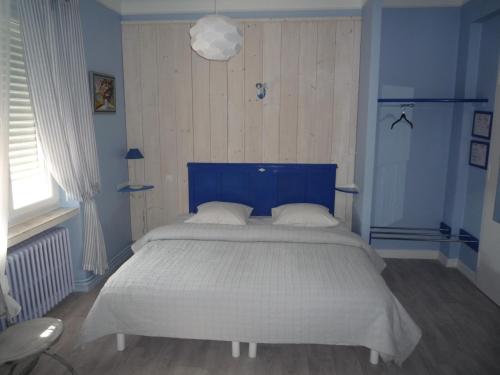a bedroom with a large bed with a blue headboard at Hotel Du Centre in Hagondange