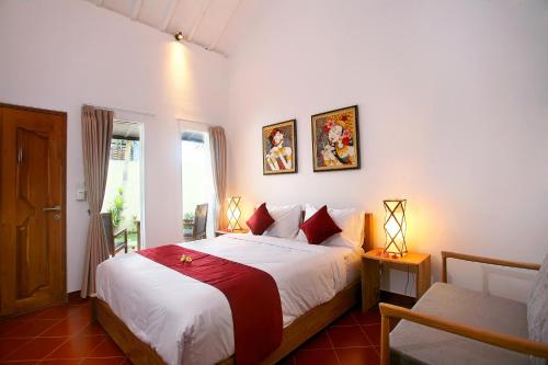 a bedroom with a bed and a window and a chair at Cokelat Guest House in Tanah Lot