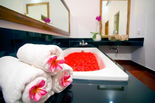 a bathroom with a bath tub with towels and red liquid at Cokelat Guest House in Tanah Lot