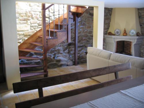 a living room with a staircase with a stone fireplace at Rústica para Férias in Mirandela