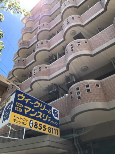 a tall building with a sign in front of it at Weekly Harbourview Mansion Main Building in Naha