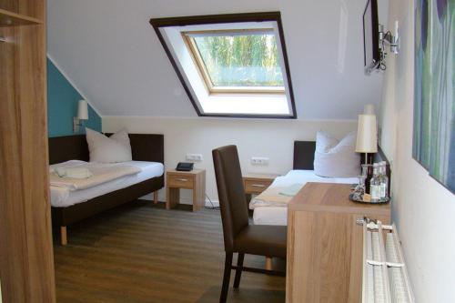 a room with two beds and a desk and a window at Hotel Restaurant Huxmühle in Osnabrück