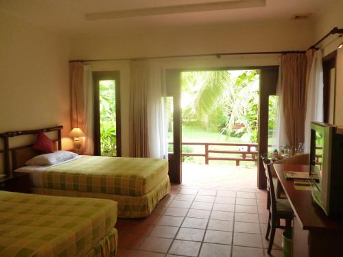 a hotel room with two beds and a sliding glass door at Can Gio Resort in Cần Giờ