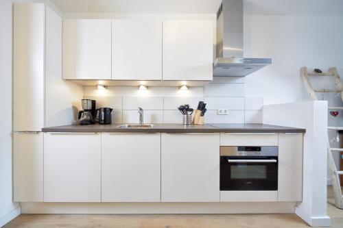 a white kitchen with white cabinets and a sink at Residenz Drachenstein Wildschönau in Niederau