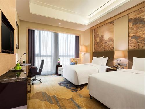 Habitación de hotel con 2 camas y escritorio en Wanda Realm Fushun, en Fushun