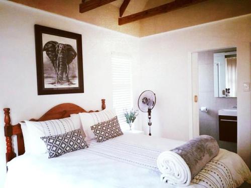 een slaapkamer met een groot wit bed met kussens bij Milnerton Guesthouse in Kaapstad