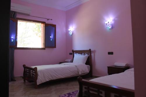 two beds in a room with pink walls and a window at Hôtel Ajil Cascades D'ouzoud in Ouzoud