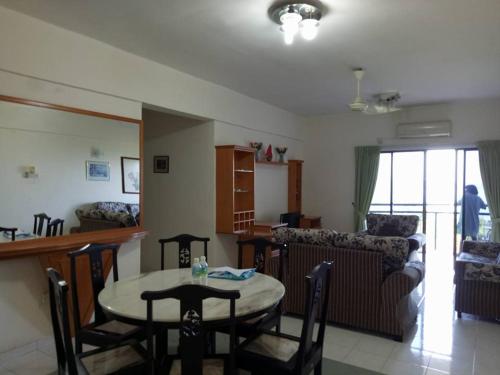 eine Küche und ein Wohnzimmer mit einem Tisch und Stühlen in der Unterkunft Lumut Valley Resort Condominium in Lumut