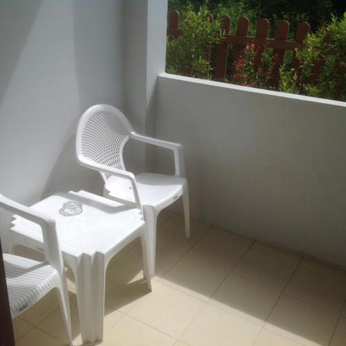 two white chairs and a table on a balcony at 2N Guesthouse in Phetchaburi