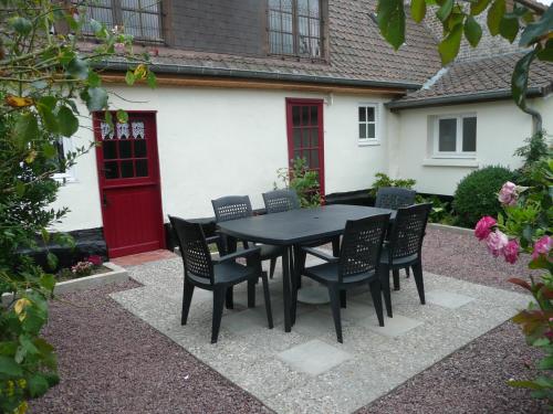 un tavolo nero e sedie di fronte a una casa di Rose Cottage En Baie De Somme a Nouvion-en-Ponthieu