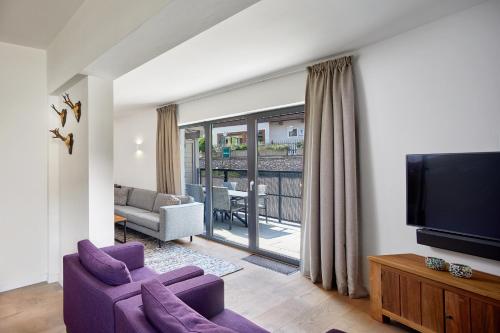 a living room with a purple couch and a tv at Kristall Plaza in Niederau