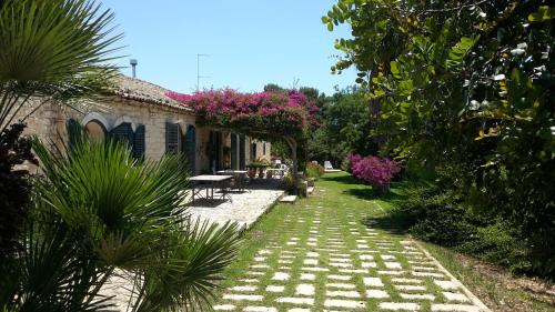 a garden path with pink flowers and a house at Case Brizza in Casale Zappulla