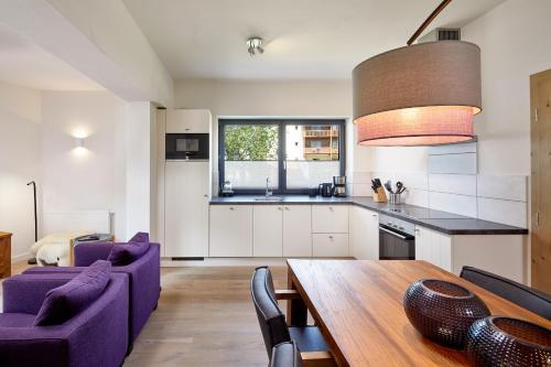 a kitchen and living room with a table and purple chairs at Kristall Plaza in Niederau